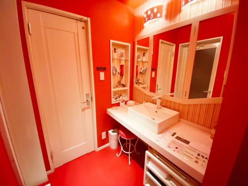 西条市YOL的浴室设有红色的墙壁、白色的盥洗盆和镜子