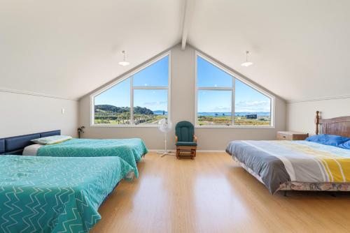 凯塔亚Tokerau Magic - Karikari Peninsula Holiday Home的带大窗户的客房内的两张床