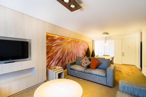 艾尔斯岩西洋鸵鸟酒店的客厅配有沙发和墙上的电视