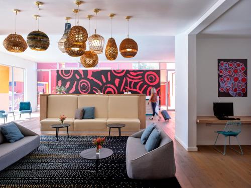 艾尔斯岩迷失骆驼酒店的客厅设有两张沙发和色彩缤纷的墙壁