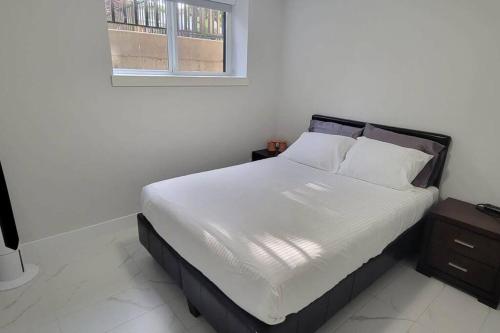 温哥华Lucy's Place - Two Bedroom Suite的一间卧室配有一张带白色床单的床和一扇窗户。