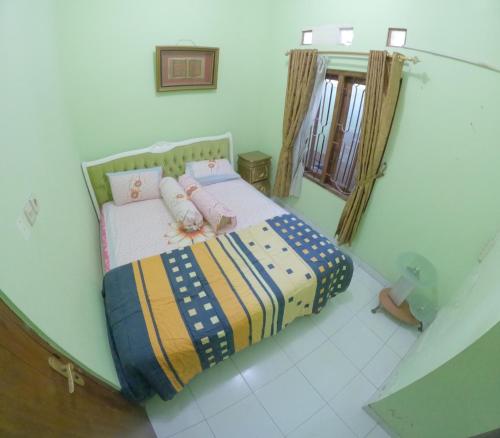 PotrojayanGrand Berbah Homestay Jogja的小卧室配有一张带彩色毯子的床