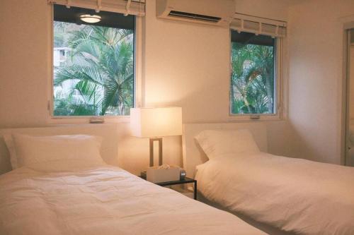 檀香山Aloha Beachfront ホノルル - Hawaii Kai的一间卧室设有两张床、一盏灯和一扇窗户。