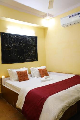 斋沙默尔Urmila Homestay的一间卧室配有一张带红色和白色枕头的大床
