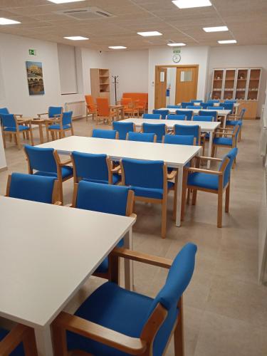 MaellaAlbergue de Maella的一个配有桌子和蓝色椅子的空教室