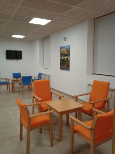 MaellaAlbergue de Maella的配有橙色椅子、桌子和屏幕的房间