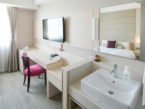 守山Vessel Inn Shigamoriyamaekimae的一间带水槽和镜子的浴室以及一张床