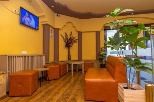 布加勒斯特加拉北站爵士酒店的一间配备有橙色家具的等候室和墙上的电视