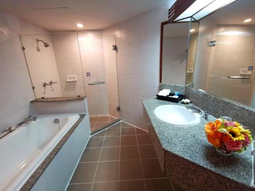 清迈Duangtawan Hotel Chiang Mai -SHA Extra Plus的带浴缸、水槽和镜子的浴室