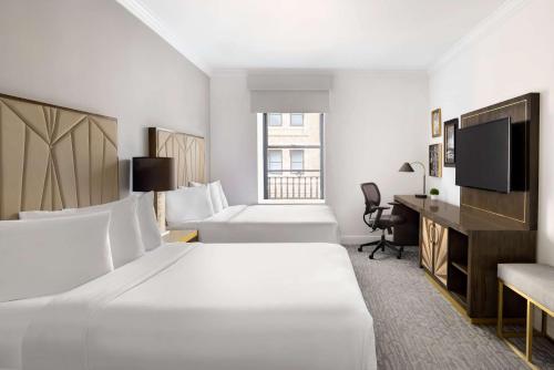 纽约Martinique New York on Broadway, Curio Collection by Hilton的酒店客房设有两张床和一台平面电视。