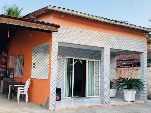 瓜鲁雅Casa espaçosa com Piscina e Churrasqueira 2 dorm的橙色和白色的房子,配有桌子和椅子