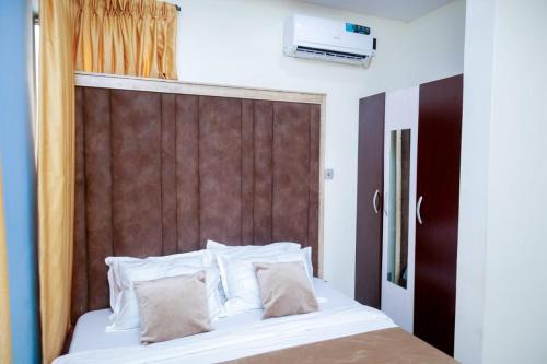 伊凯贾GOD'S TOUCH APARTMENTS SHORT-LET Adenugba Street Oregun Ikeja Lagos Nigeria的一张带白色枕头和棕色床头板的床