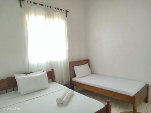 拉穆Manama Suites Apartment的客房设有两张床和窗户。