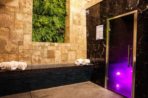 塔德卡斯特Hazlewood Castle & Spa的浴室在紫色光的台面上配有毛巾