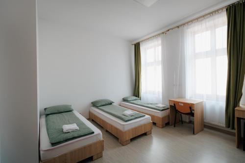 奥拉迪亚Collegium Varadinum的客房设有两张床、一张书桌和窗户。