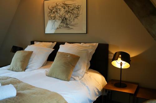 索姆河畔的圣瓦列里Maison d'hôtes du Jardin的一间卧室配有带白色枕头和灯的床