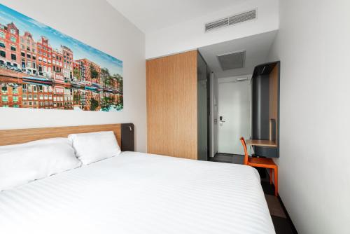 阿姆斯特丹阿姆斯特丹竞技场大道便捷酒店的卧室配有一张床,墙上挂有绘画作品