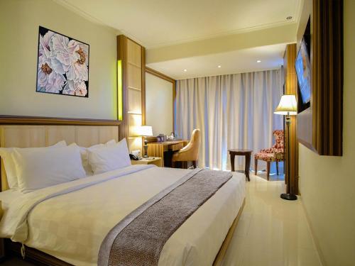 塞尔蓬Sapphire Sky Hotel & Conference的酒店客房设有一张大床和一张书桌。