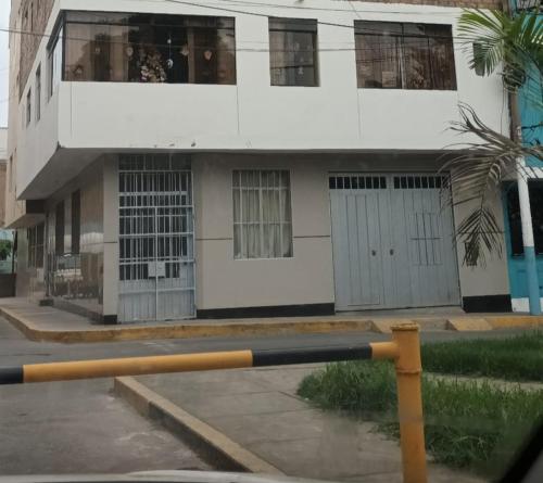 利马Habitación 2 camas a pasos del Aeropuerto Lima的一座白色的建筑,前面有棕榈树