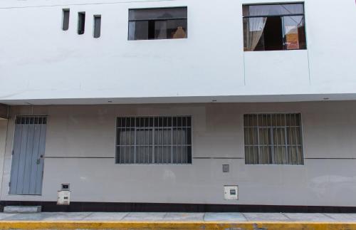 利马Habitación 2 camas a pasos del Aeropuerto Lima的白色的建筑,有四扇窗户和门