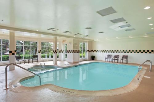 奥克布鲁克特莱斯希尔顿花园奥克布鲁克特莱斯酒店的一个带桌椅的房间的大型游泳池