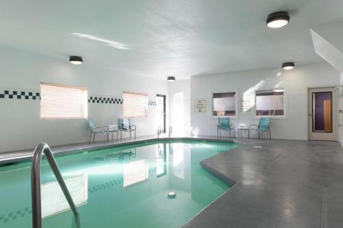 泰格德提加波特兰希尔顿逸林酒店的大楼内带蓝色椅子的游泳池