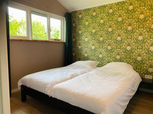 LeuvenheimGastenverblijf in rustige groene omgeving - Kievit Leuvenheim的卧室内的一张床铺,墙上挂着鲜花