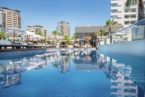 巴塞罗那希尔顿巴塞罗那对角线三月酒店的一座棕榈树和建筑的大型游泳池