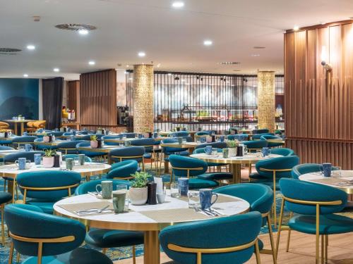 巴塞罗那希尔顿巴塞罗那对角线三月酒店的一间配备有桌子和蓝色椅子的用餐室