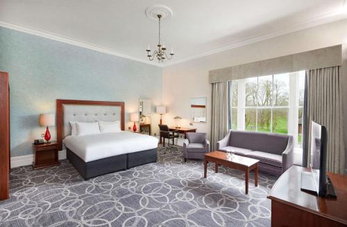 格洛斯特Hilton Puckrup Hall Hotel & Golf Club, Tewkesbury的酒店客房设有床和客厅。