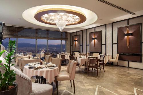 伯萨布尔萨希尔顿会议&Spa酒店的一间带桌椅和吊灯的用餐室