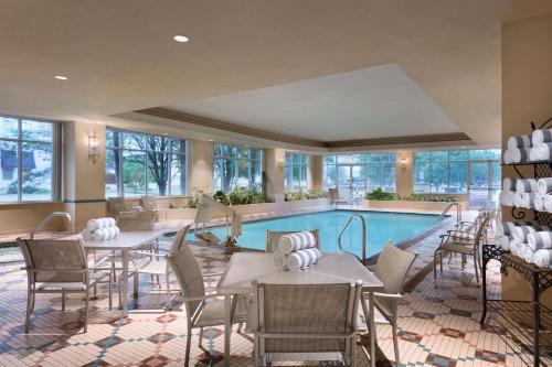 查尔斯顿查尔斯顿合博套房酒店的一个带桌椅的泳池间和一个游泳池