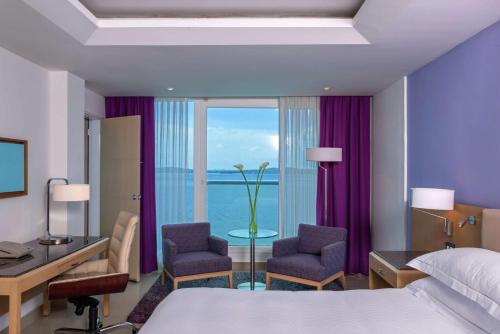 卡塔赫纳卡塔赫纳希尔顿酒店的酒店客房,配有一张床、一张桌子和椅子