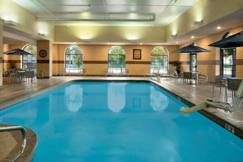 德梅因得梅因市中心大使套房酒店的酒店的大型游泳池配有桌椅