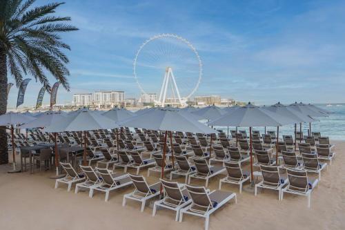迪拜迪拜希尔顿沃克酒店的沙滩上的一把椅子和遮阳伞