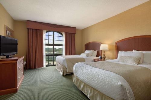 格林斯伯勒Embassy Suites by Hilton Greensboro Airport的酒店客房设有两张床和一台平面电视。