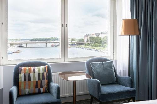 赫尔辛基赫尔辛基斯特兰德希尔顿酒店的窗户客房内的两把椅子和一张桌子