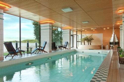 赫尔辛基希尔顿赫尔辛基卡拉斯塔佳图帕酒店的大楼内一个带桌椅的游泳池