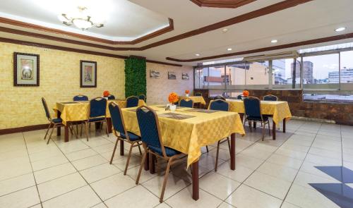 瓜亚基尔马雷贡酒店的餐厅设有桌椅和黄色桌布