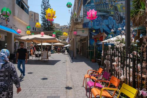内坦亚Appartement cosy sur Netanya的一位妇女沿着街上走,手里拿着椅子和桌子