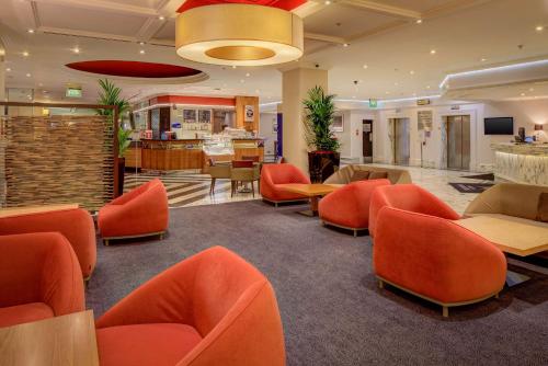 利兹希尔顿利兹城市酒店的大堂的等候区配有橙色椅子和桌子