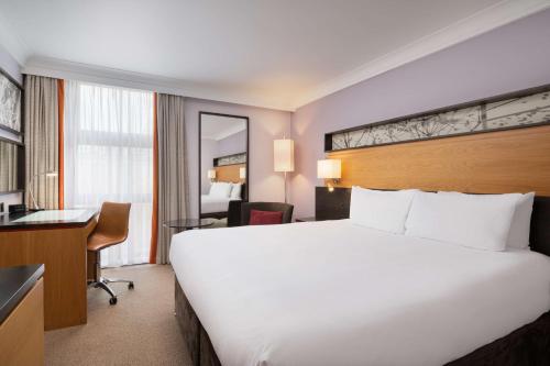 伦敦希尔顿伦敦肯辛顿酒店的酒店客房设有一张白色大床和一张书桌
