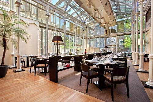 伦敦希尔顿伦敦尤斯顿酒店的餐厅设有桌椅和窗户。
