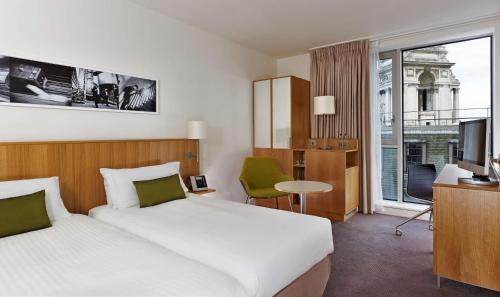 伦敦伦敦塔希尔顿逸林酒店的酒店客房设有一张床和一个大窗户