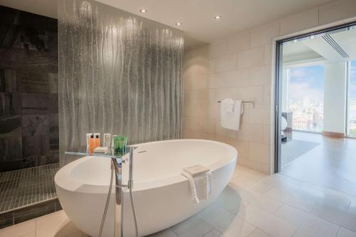 利物浦利物浦市中心希尔顿酒店的白色的浴室设有浴缸和淋浴。