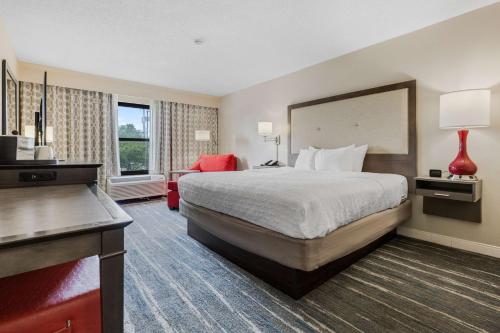 孟菲斯孟菲斯沃夫彻斯商业街廊希尔顿恒庭旅馆&套房酒店的酒店客房设有一张大床和一张红色椅子。