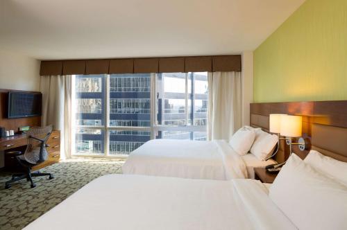 纽约纽约曼哈顿市中心东希尔顿花园酒店的酒店客房设有两张床、一张书桌和一个窗户。