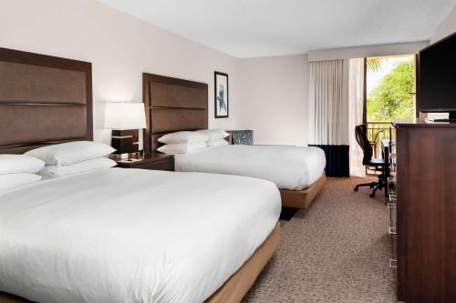 棕榈滩花园棕榈滩花园希尔顿逸林酒店的酒店客房配有两张床和一张书桌