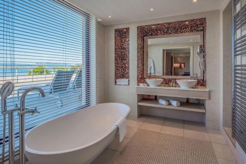 埃维昂莱班希尔顿伊凡乐班酒店的带浴缸、两个盥洗盆和镜子的浴室