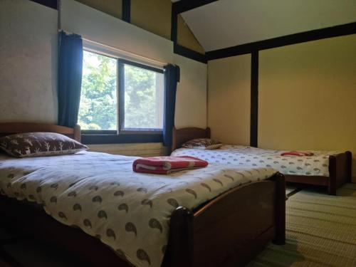 富良野Bears House的带窗户的客房内设有两张单人床。